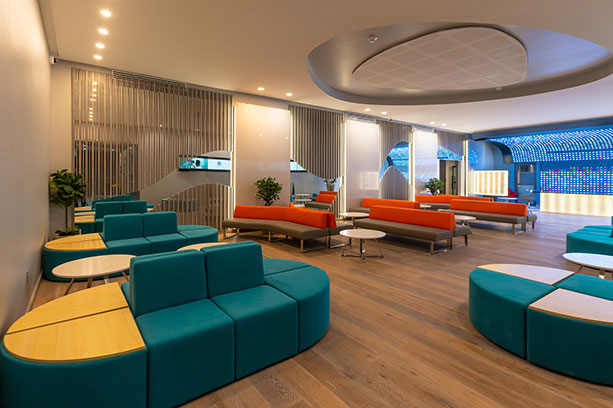 A lobby with blue and orange couches and tables.
